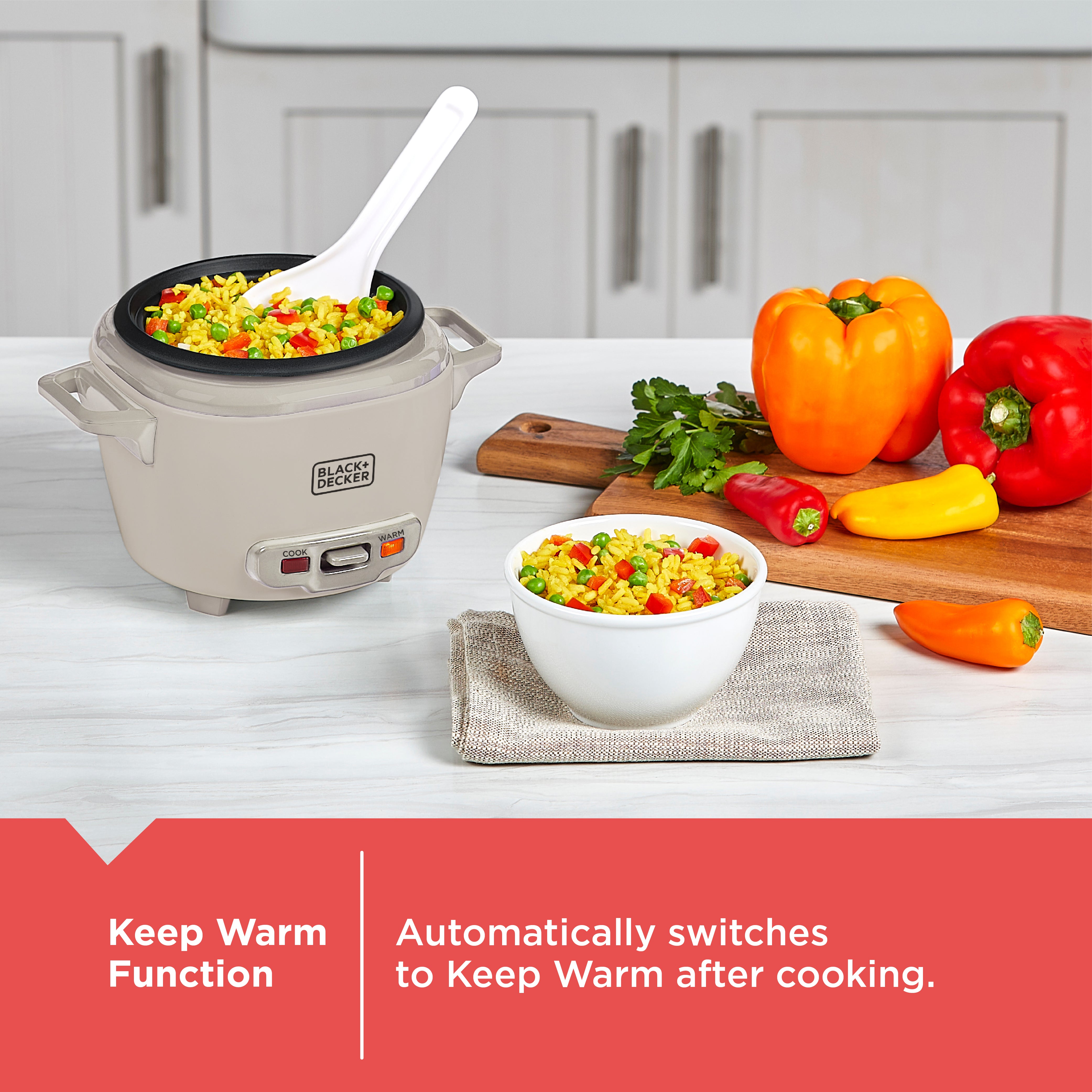 Rice cooker with cooked vegetables, a bowl of rice, and colorful peppers on a kitchen counter.