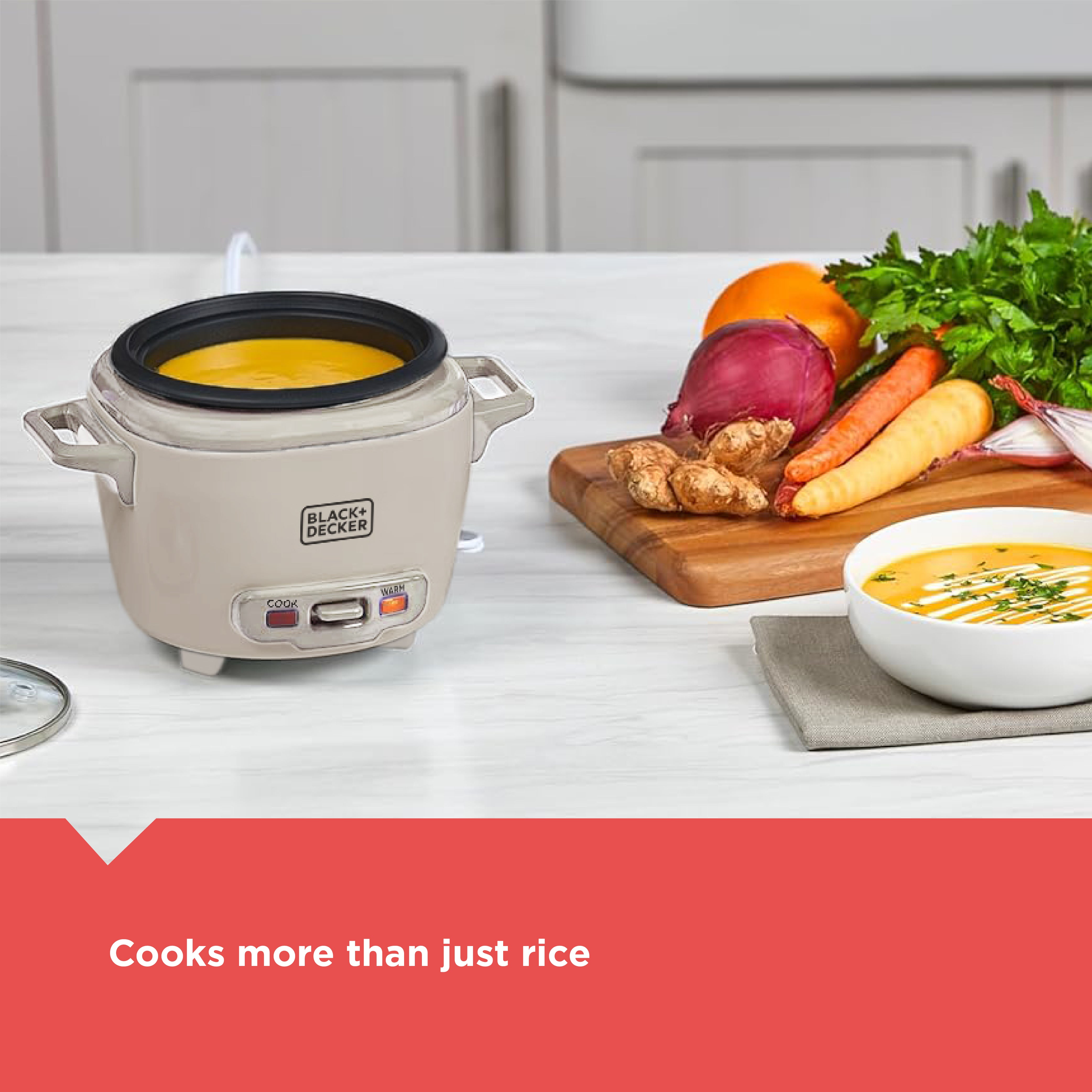 Black+Decker rice cooker with a bowl of soup and vegetables on a kitchen counter.