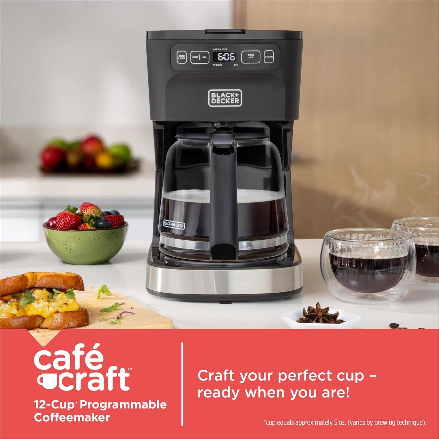 Black+Decker coffee maker on a kitchen counter with fruit and coffee cups.