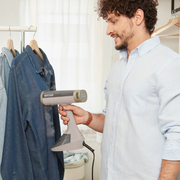 man steaming denim shirt on hanger