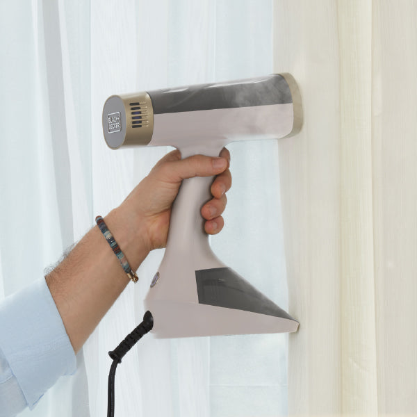 closeup of handheld steamer steaming curtains