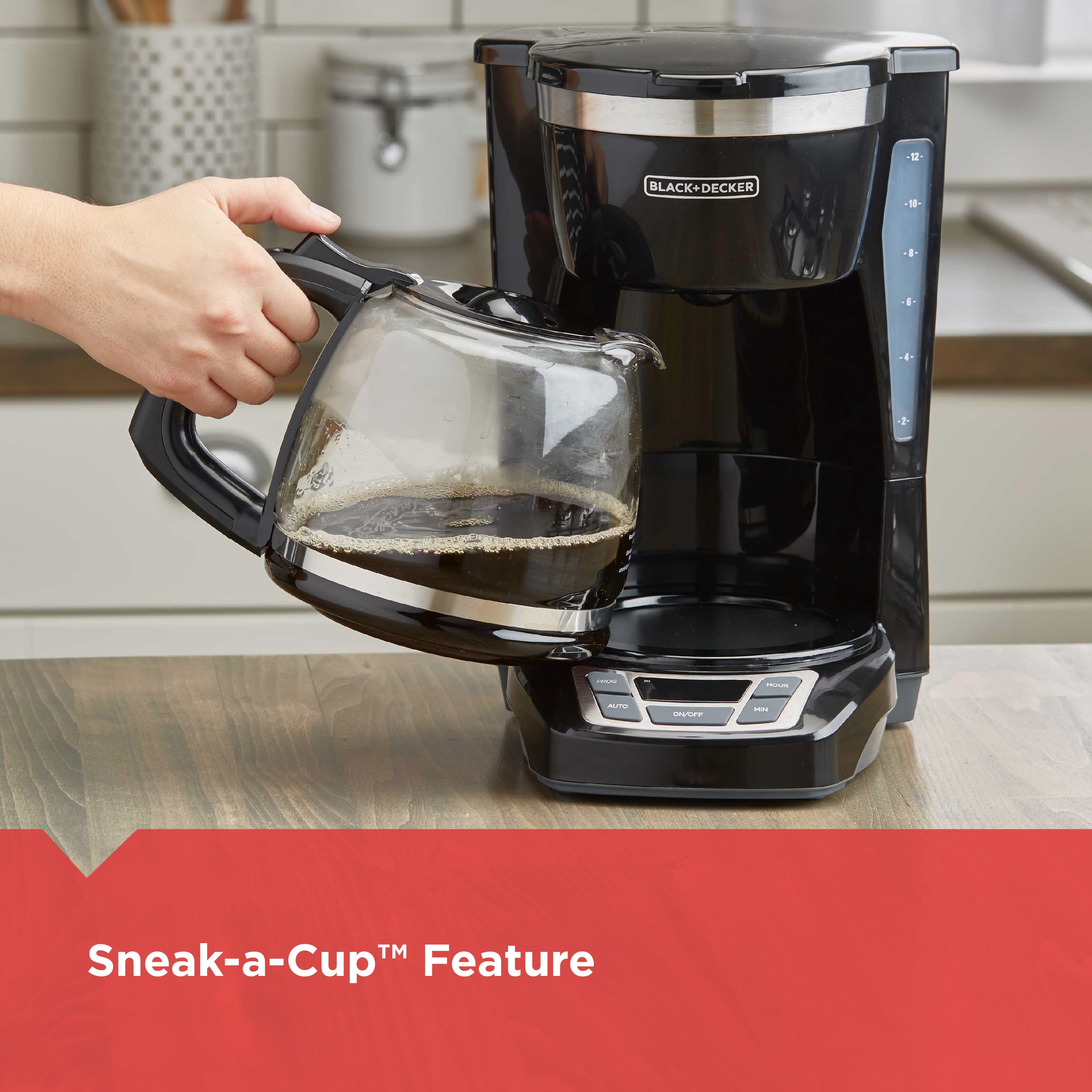 Black and Decker coffee maker with a person pouring coffee into a glass carafe on a kitchen counter.