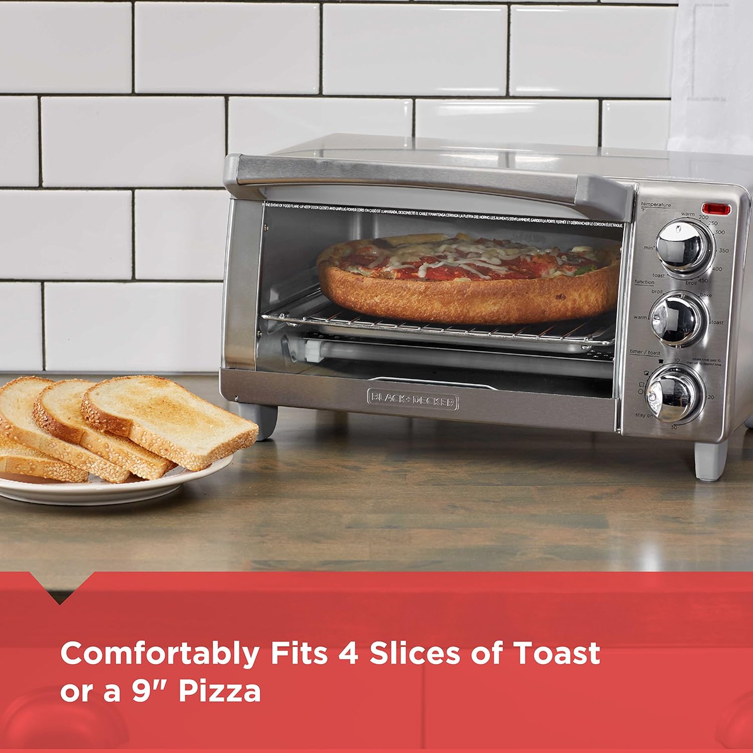 Toaster oven with a pizza inside, next to a plate of toast, on a kitchen counter.