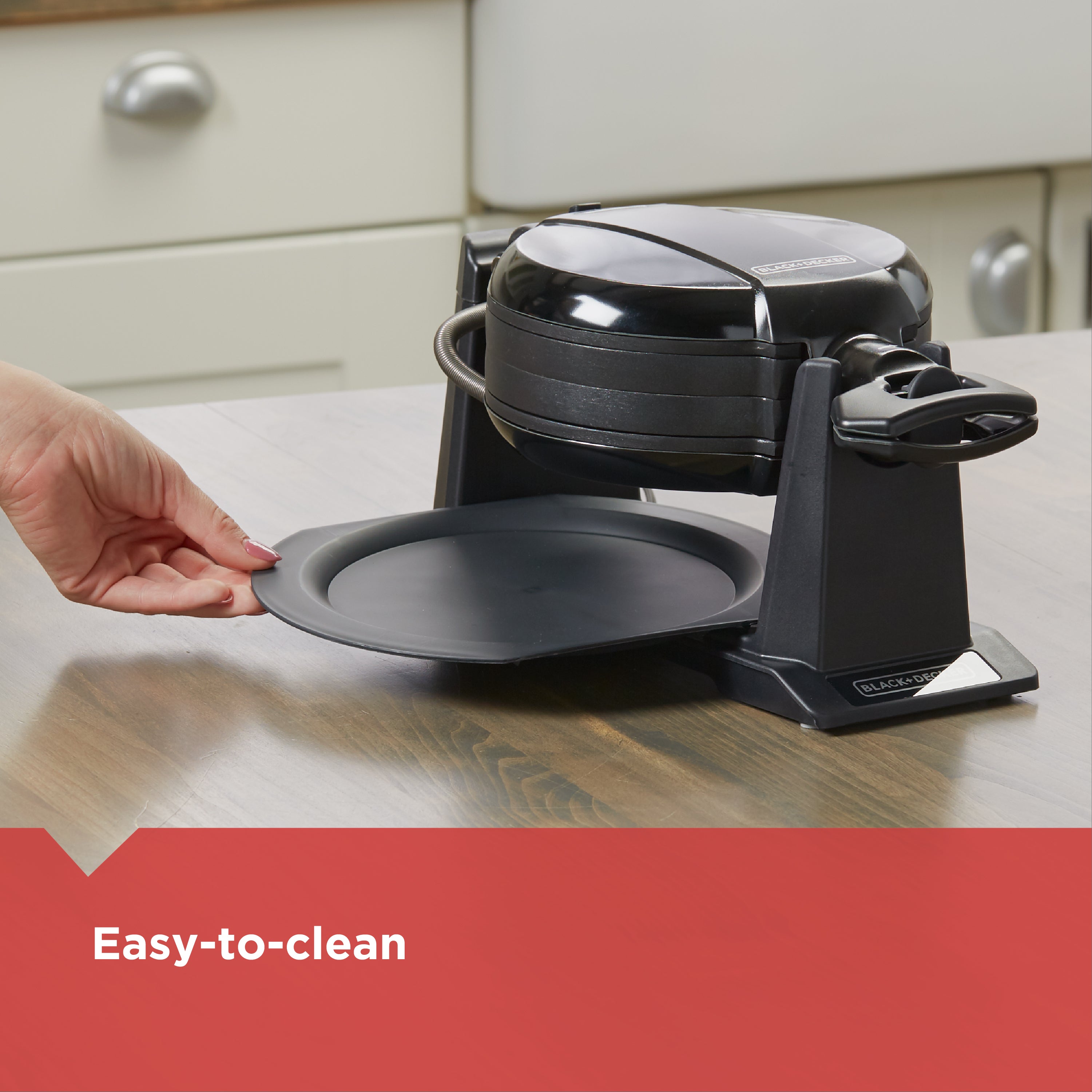 Black waffle maker on a kitchen counter with a hand lifting a plate, labeled 'Easy-to-clean'.