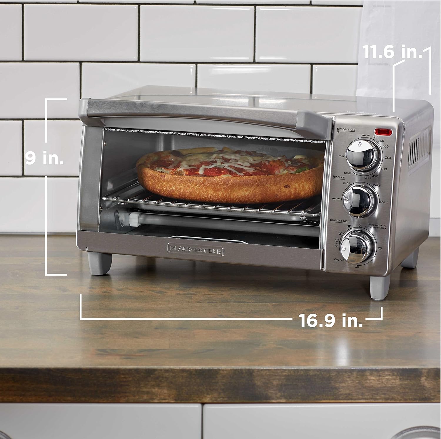 Silver toaster oven with pizza inside, showing dimensions on a kitchen counter.