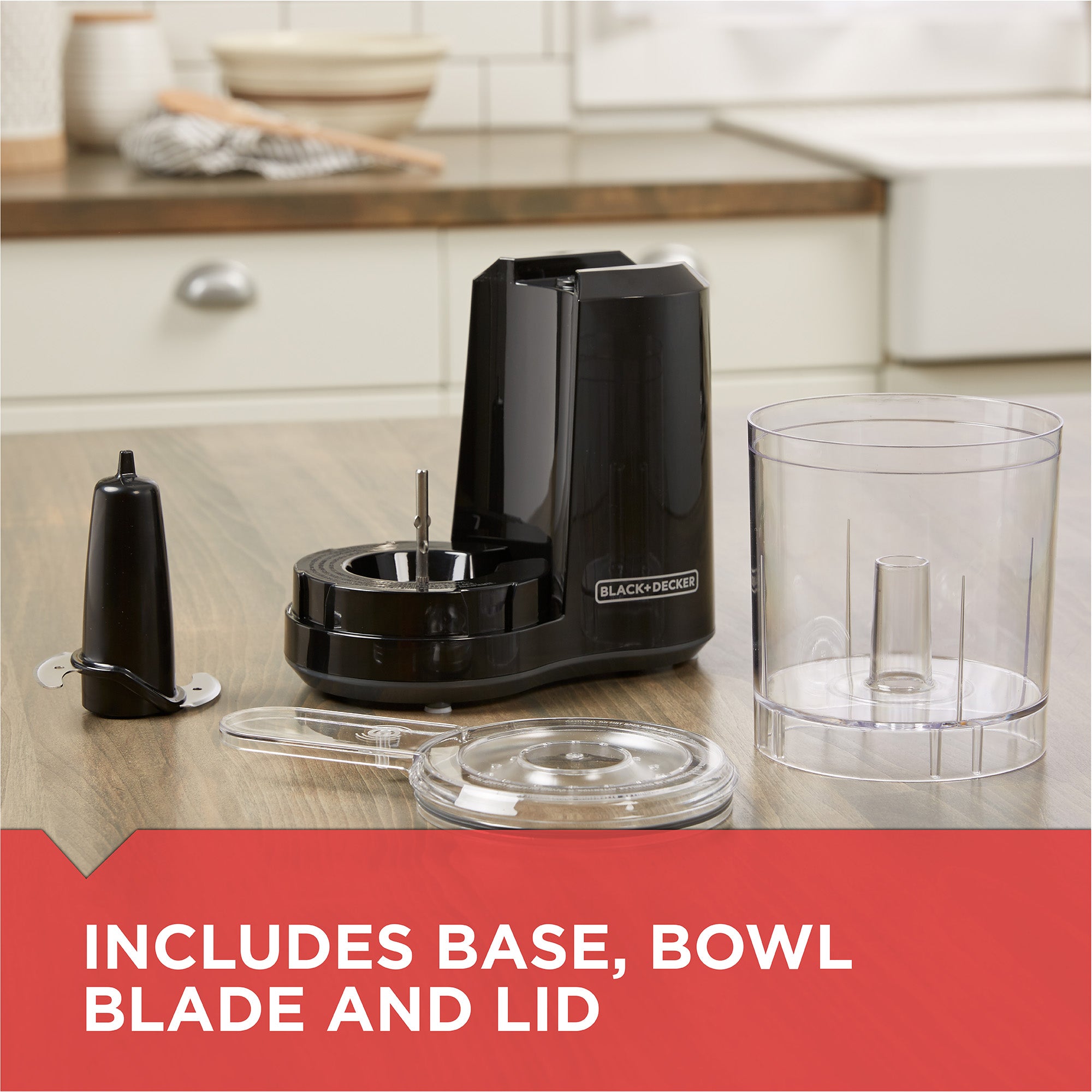 Black kitchen appliance with base, bowl, blade, and lid on a kitchen counter.