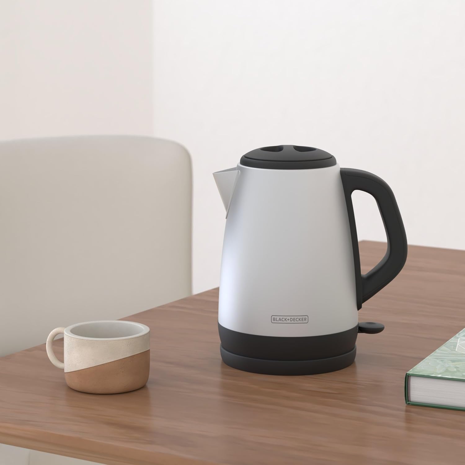 White electric kettle with black handle and base on a wooden table.