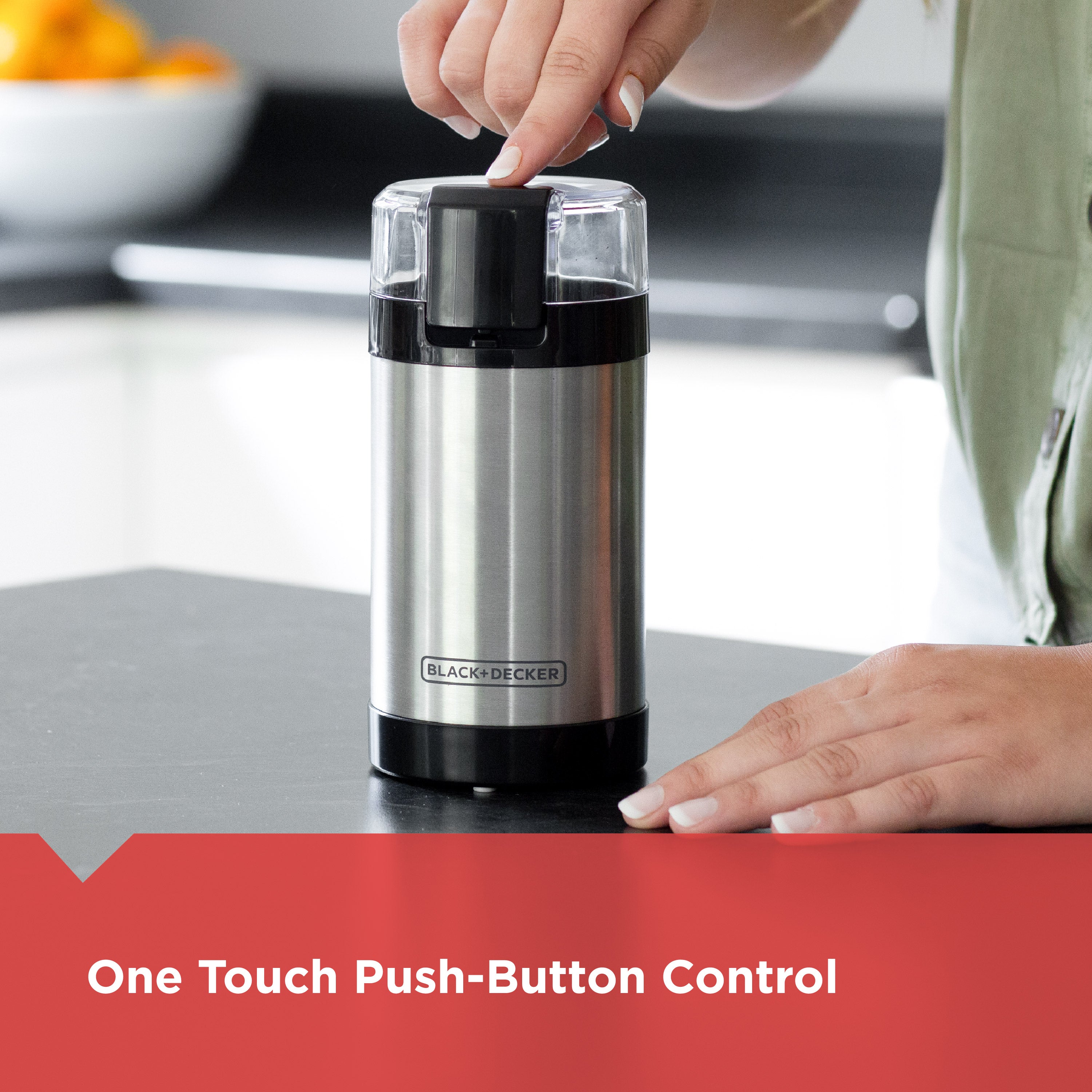 Black & Decker coffee grinder on a kitchen counter with a hand pressing a button.