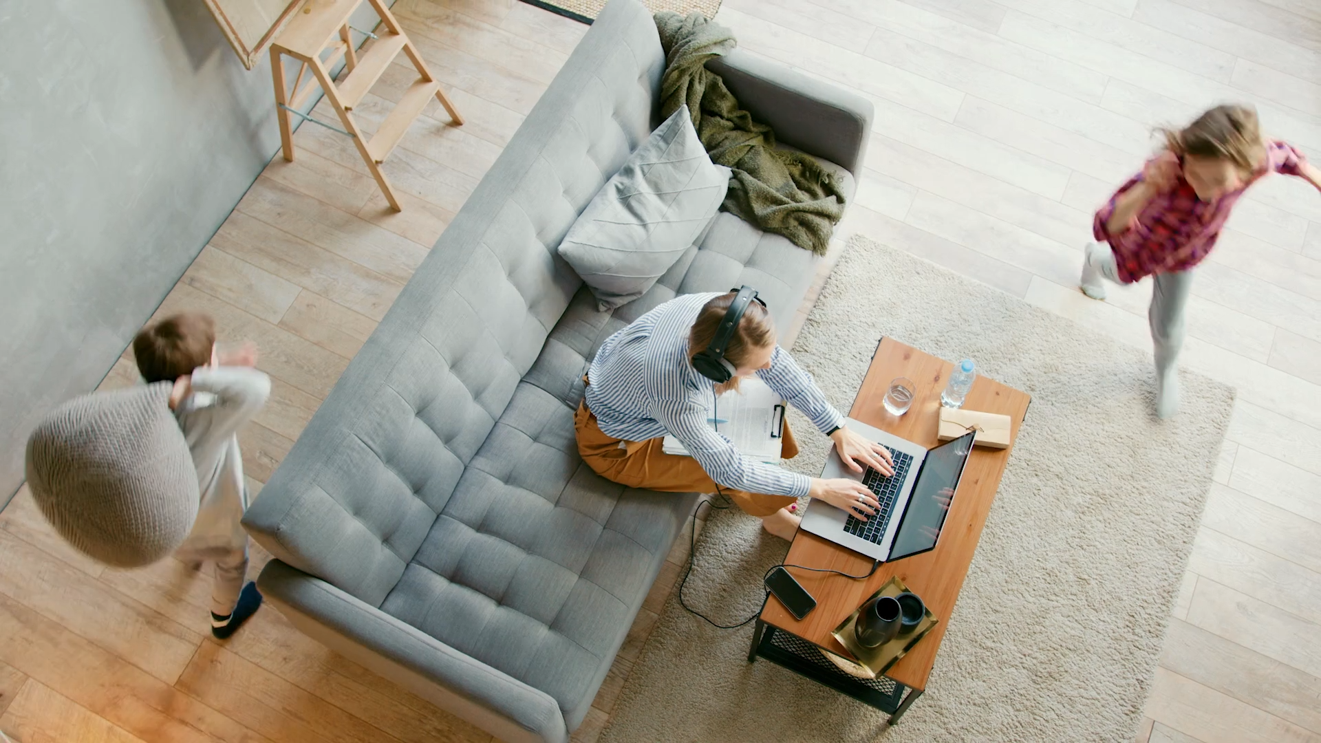 Person working on a laptop in a living room with a couch and coffee table.