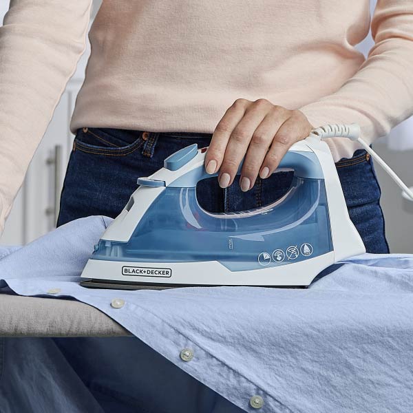 Person ironing a shirt with a Black+Decker iron on an ironing board.