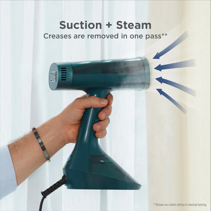 Hand holding a green steam cleaner with text 'Suction + Steam Creases are removed in one pass' against a white curtain background.