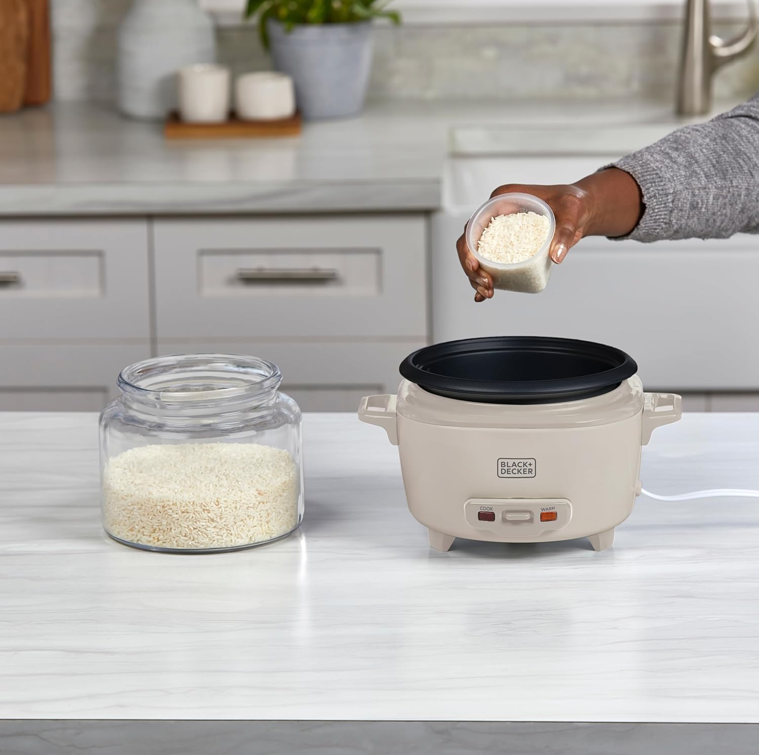 Person adding rice to a rice cooker on a kitchen counter