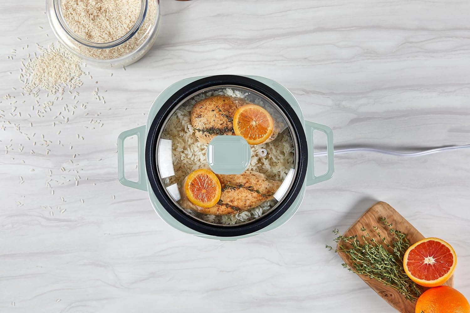 Cooking pot with food on a light gray surface, surrounded by oranges and oats.
