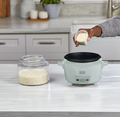 Person adding rice to a rice cooker on a kitchen counter