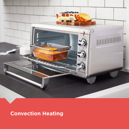 Stainless steel toaster oven with convection heating feature, displaying food inside.