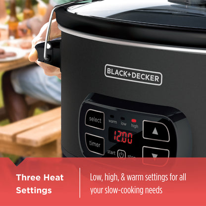 Black+Decker slow cooker with digital display and control panel, set on a blurred outdoor background.