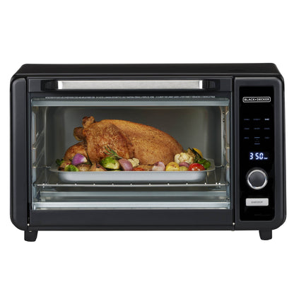 Black toaster oven with a roasted turkey and vegetables inside on a white background