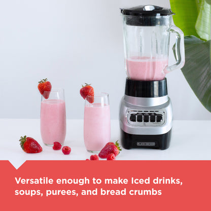 Blender with pink smoothie and glasses of smoothie on a white surface with strawberries.