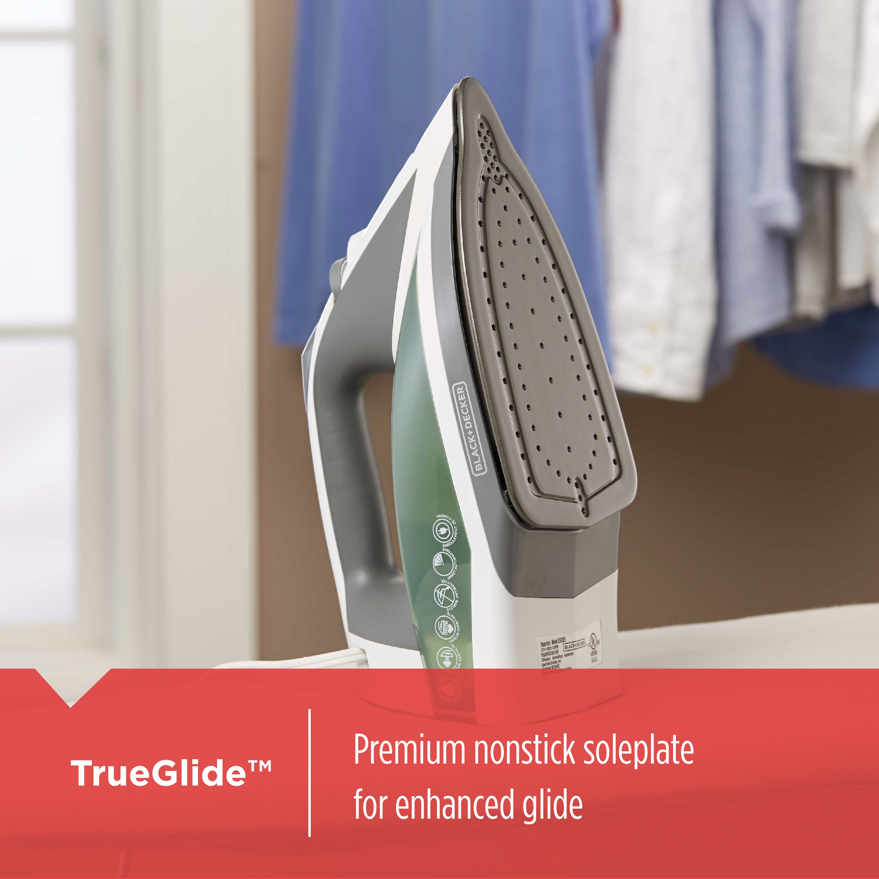 Steam iron with 'TrueGlide' feature on a blurred background of clothes and window.