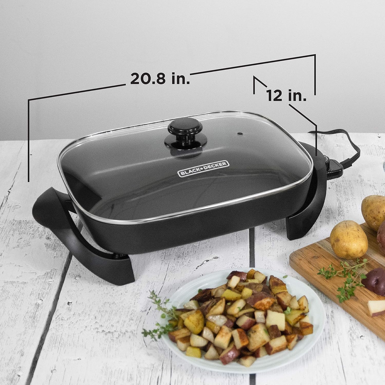 Black and Decker electric skillet with dimensions labeled on a white surface with food.